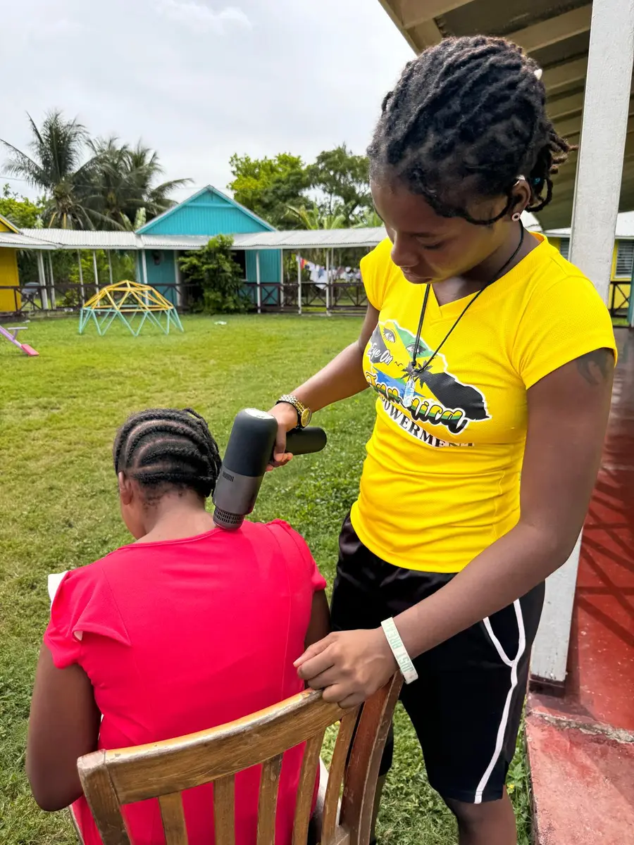 A volunteer braiding a child’s hair during a self care day